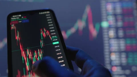 A hand is engaging actively with a stock trading application displayed on a Stock Footage 317036281