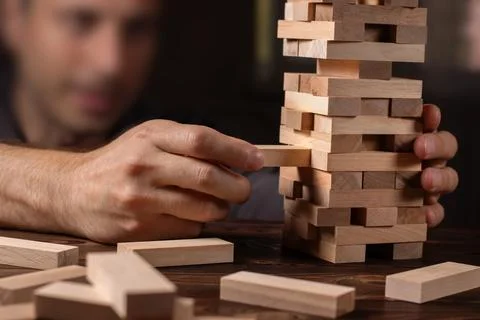 Hand of engineer playing a blocks wood tower game on blueprint or architect.. Stock Photos