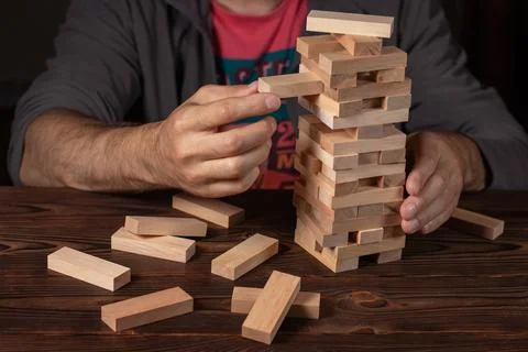 Hand of engineer playing a blocks wood tower game on blueprint or architectur Stock Photos