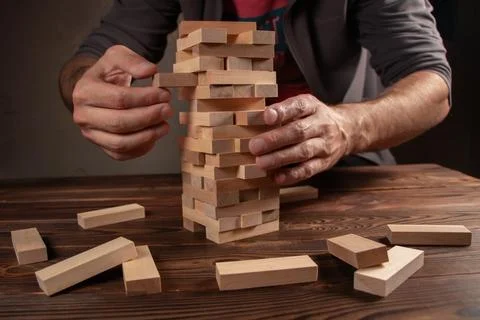 Hand of engineer playing a blocks wood tower game on blueprint or architectur Stock Photos