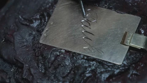 Hand engraving elegant cursive script letters into gold jewelry pendant closeup Stock-Footage 323314521