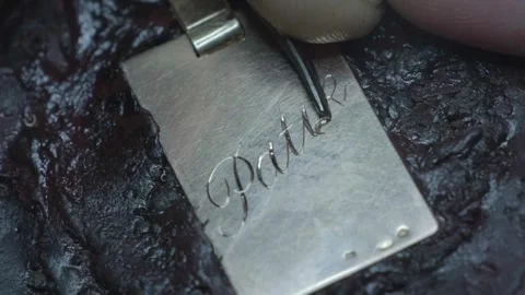Hand engraving elegant cursive script letters into gold jewelry pendant closeup Stock-Footage 323314711