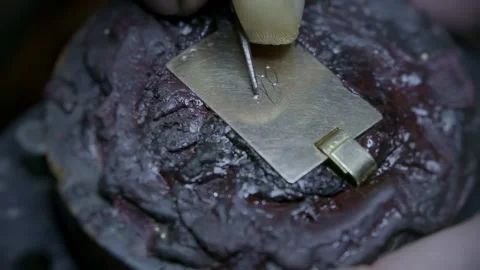 Hand engraving elegant cursive script letters into gold jewelry pendant closeup Stock-Footage 323383250