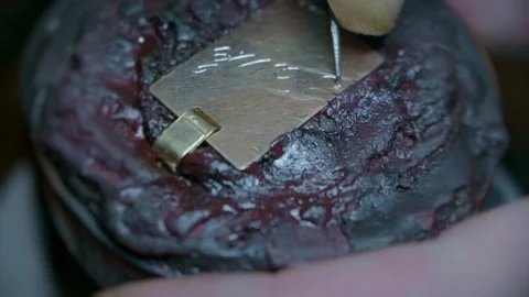 Hand engraving elegant cursive script letters into gold jewelry pendant closeup Stock-Footage 323383276