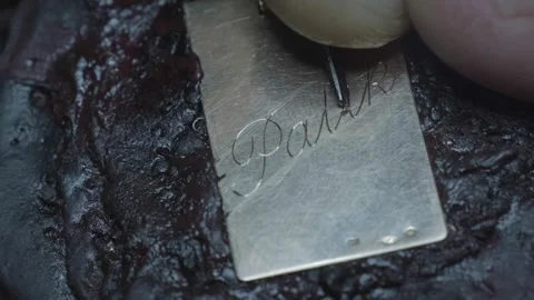 Hand engraving elegant cursive script letters into gold jewelry pendant closeup Stock-Footage 323383288