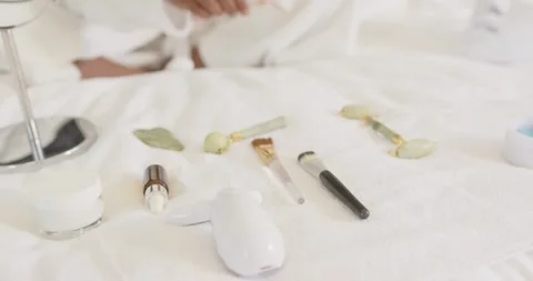 Hand entering frame, picking up pink pot, arranging jade rollers and brushes on Stock Footage 336306005