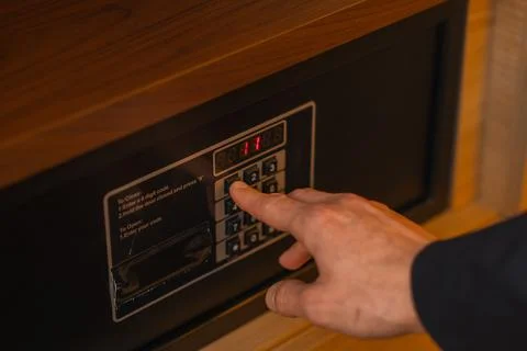 A hand enters a code to open and lock a safe or safe in a hotel room Theft or Stock Photos