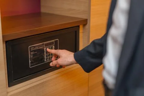 A hand enters a code to open and lock a safe or safe in a hotel room Theft or Stock Photos