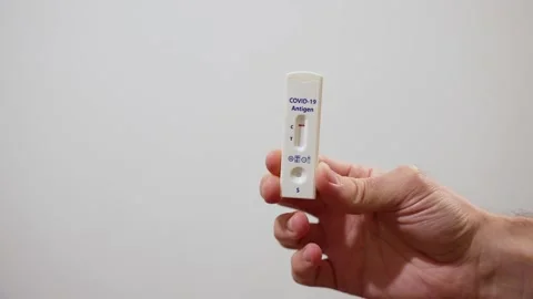 Hand enters frame to show negative result on device for antigen home quick test Stock Footage 169409690