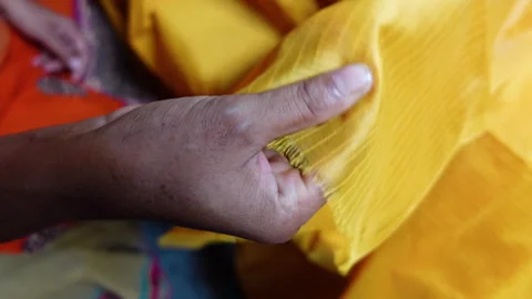 A hand examining a yellow loom cloth made of silk thread. Stock Footage 263971981