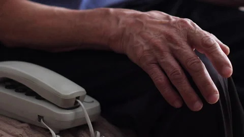 The hand of an excited old man sitting near a push-button wire telephone an.. Vídeos de archivo 240460281