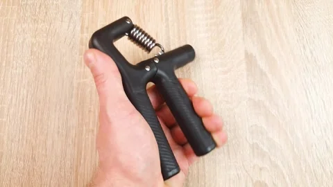 Hand expander. A man is holding the exercise tool in his hand. Vídeos de archivo 347090363