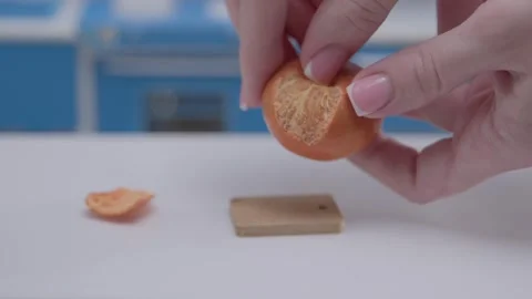 Hand expertly peels an orange using miniature cookware in a tiny kitchen Video stock 286898799