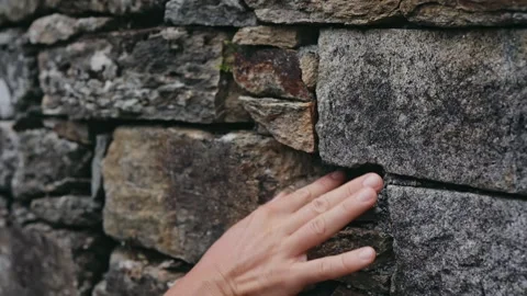 The hand exploration the stone surface of the wall, picks the stone, studies the Stock Footage 243726992