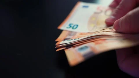 Hand fans a stack of 50 euro banknotes on a dark table with copy space Vidéo 328951207