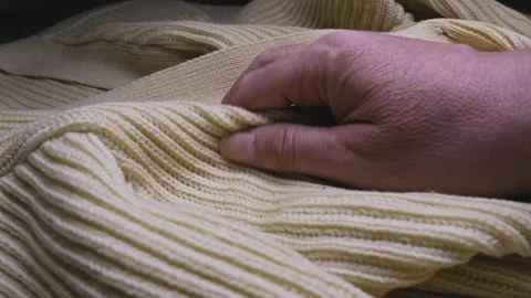 Hand feeling the texture and ribbed pattern of a knitted Wool jumper Stock Footage 308916976