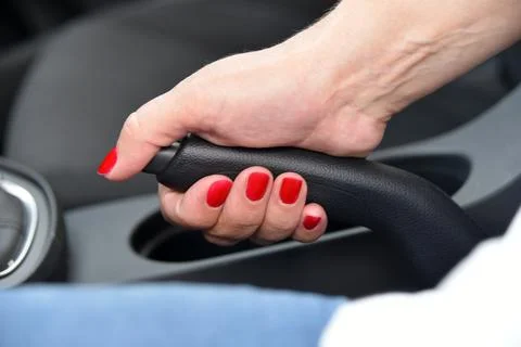 Hand female driver pulling the hand brake inside car Stock Photos