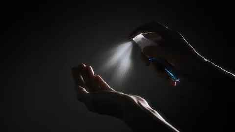 Hand female using alcohol spray on dark background Stock Footage 129796376