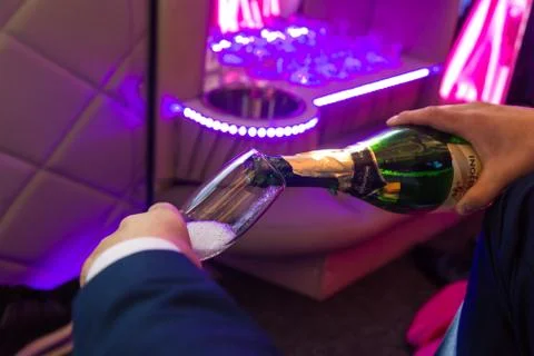 Hand fills champagne flutes in the limusine with back light Stock Photos