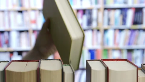 Hand finding a book on bookshelf in the library Vidéo 301067847