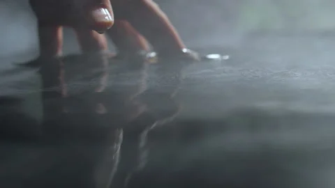 Hand with fingers touching the water surface. Smoke flowing over the water. Slow Stock Footage 156542419