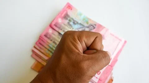 Hand in Fist Gesture Over Stack of Indonesian Rupiah Banknotes Foto stock