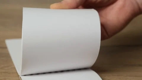 Hand flipping empty notebook pages on a wooden table. Close up Stock Footage 125266661