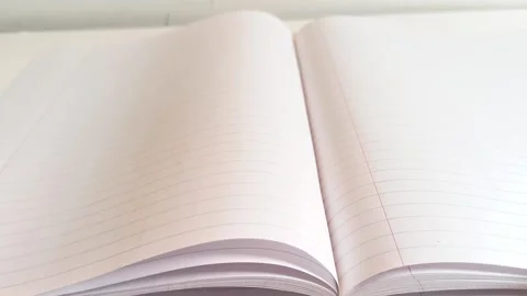 Hand flipping through a notebook, turning white lined paper pages on desk table 動画素材 317135416