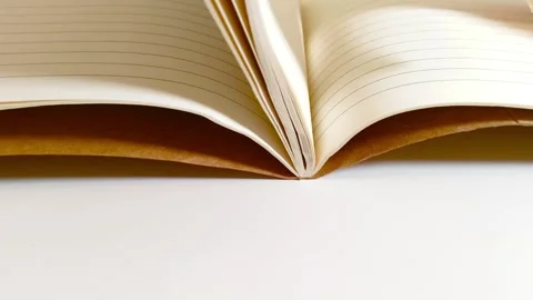 Hand flipping through a notebook, turning white lined paper pages on desk table 動画素材 317135426