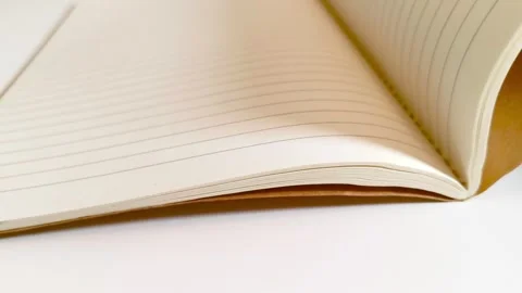 Hand flipping through a notebook, turning white lined paper pages on desk table 動画素材 317135463