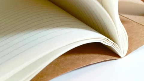 Hand flipping through a notebook, turning white lined paper pages on desk table 動画素材 317135464