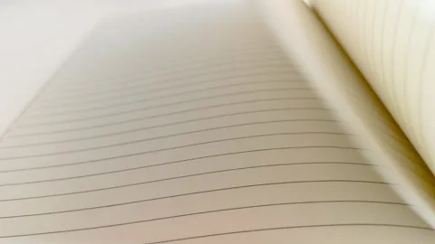 Hand flipping through a notebook, turning white lined paper pages on desk table 動画素材 317135465