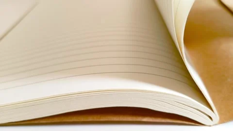 Hand flipping through a notebook, turning white lined paper pages on desk table 動画素材 317135466