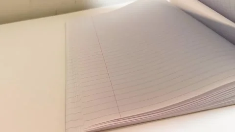 Hand flipping through a notebook, turning white lined paper pages on desk table 動画素材 317135473