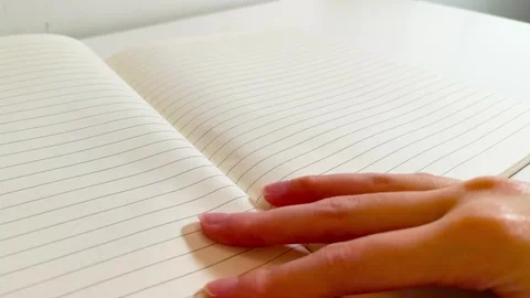 Hand flipping through an open notebook with white lined paper pages turning.. Stockbeeldmateriaal 317135395