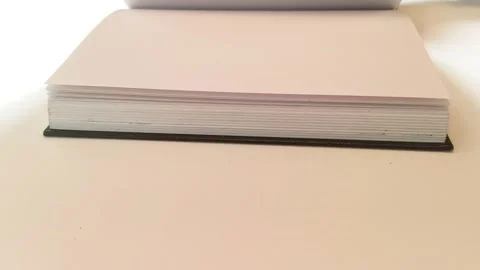Hand flipping through an open sketchbook with paper pages turning on desk table 動画素材 317135352