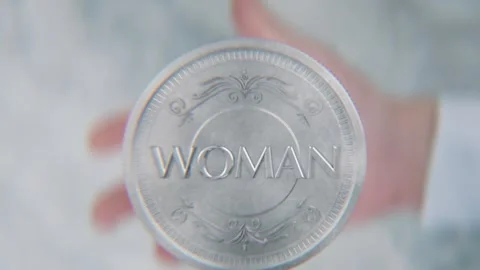 A hand flips a coin marked Man and Woman, spinning toward the camera in slo.. Stock Footage 296366837