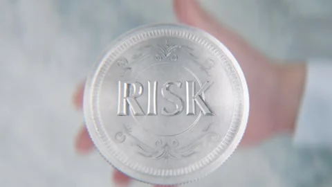 A hand flips a coin marked Risk and Safety, spinning toward the camera in s.. Stock Footage 296366843