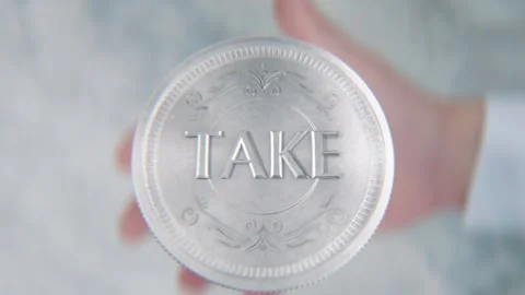 A hand flips a coin marked Take and Give, spinning toward the camera in slo.. Stock Footage 296366845