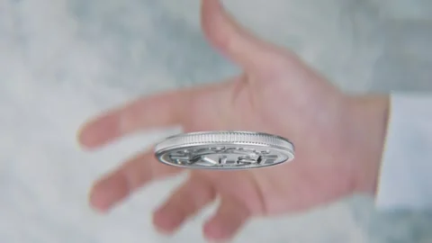 A hand flips a coin marked True and False, spinning toward the camera in slow .. Video stock 293790883