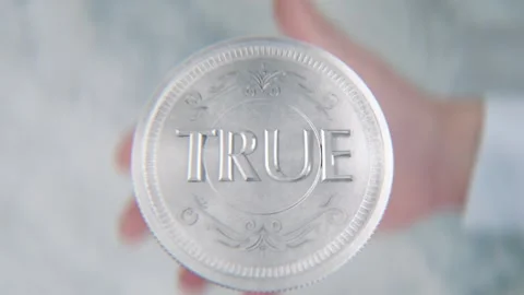 A hand flips a coin marked True and False, spinning toward the camera in sl.. Stock Footage 296366811