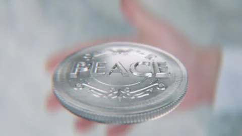 A hand flips a coin marked War and Peace, spinning toward the camera in slo.. Stock Footage 293780052