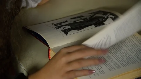Hand flips pages in a book to read Stock Footage 122096946