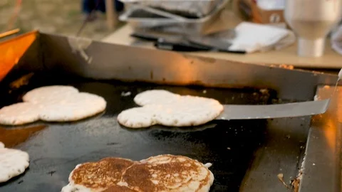 Hand flips several mickey shaped pancakes on large grill slow motion Stock Footage 94219654