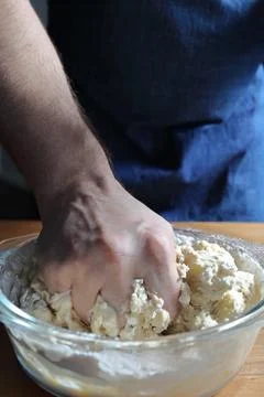 Hand forcefully kneading bread dough in glass bowl Stock Photos