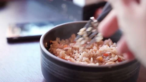 A hand with a fork mixes hot rice with vegetables. Tyahan. Stock Footage 197933202