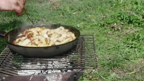 A hand with a fork tries on readiness fried potatoes in a pan on the grill, 스톡 동영상 217515962