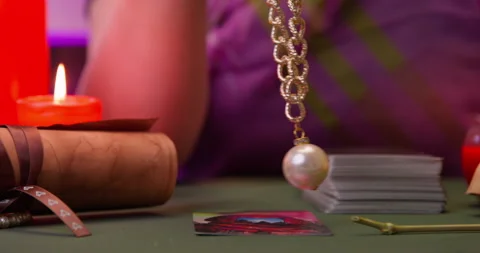 Hand of fortune teller swings a pendulum medallion over cards, prediction, past Video stock 257732783
