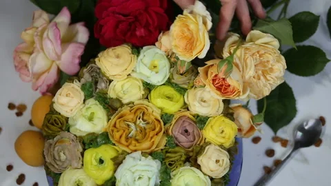 The hand in the frame puts a branch of a live yellow rose on the cake. The pastr Stock Footage 143676087