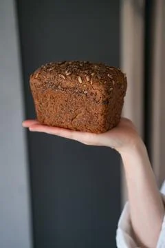 Hand with a fresh bread on a dark background closeup Stock Photos
